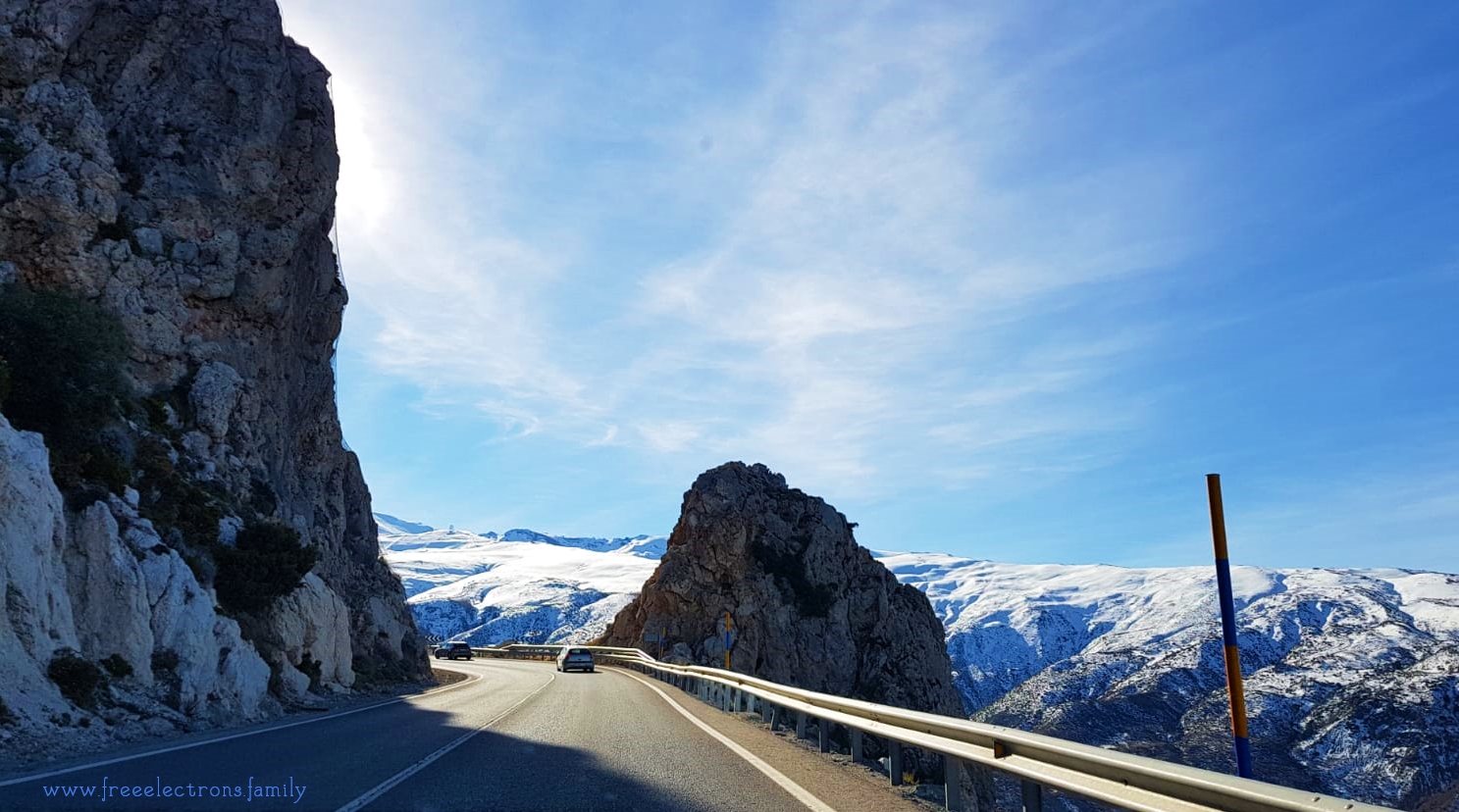 Photo of the road to Hoya de la Mora snow resport of the Sierra Nevada, Granada in Andalucia, Spain.

Picture shows a paved 2-lane road with guardrails.  In the distance snow-covered mountain and clear blue Andalusian sky.

Caption reads:  Snow at last, SNOW AT LAST!  On a Sunday morning, you can drive all the way up to Hoya de la Mora resort and even find parking if you get there early enough.

www.freeelectrons.family