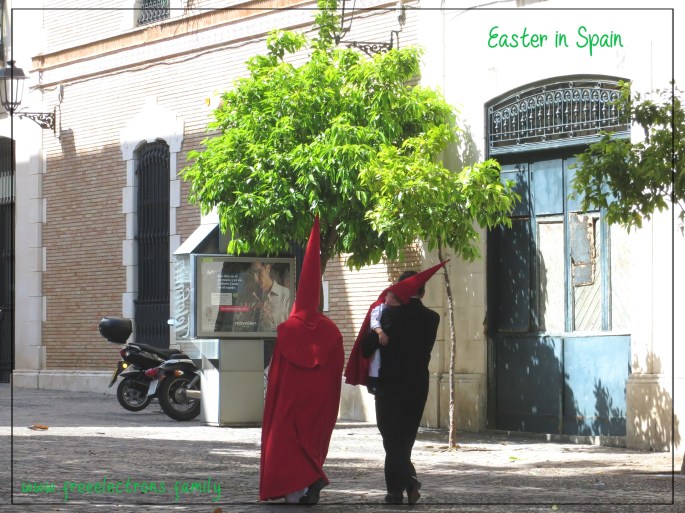 Walking alongside a hooded penitent wife, a father carries a sleeping child, after a Holy Week (Semana Santa) procession in Jerez de la Frontera, Andalucia, Spain. Location: Plaza del Banco.
