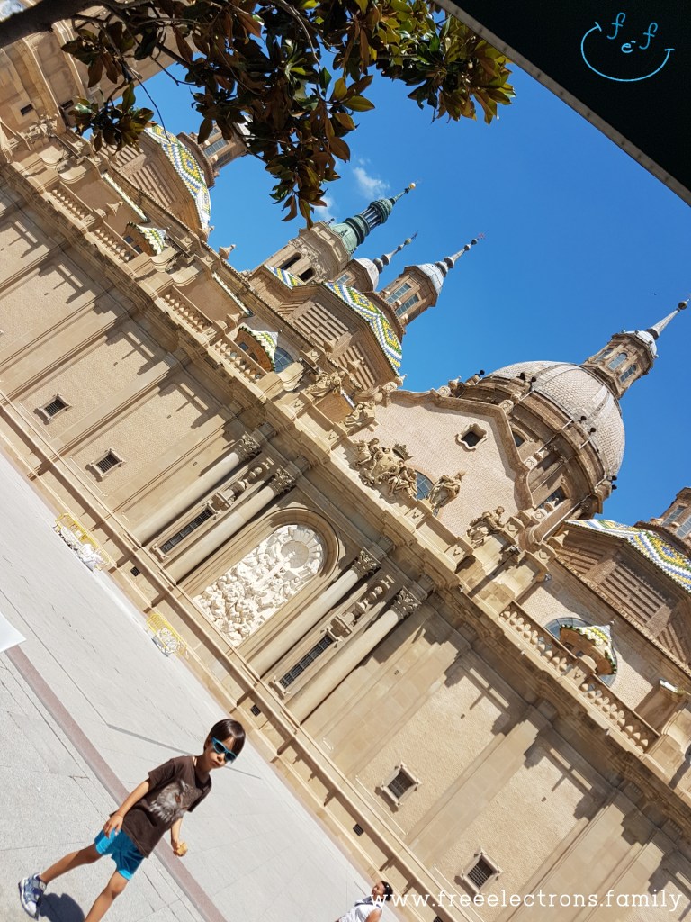 Third stop on our #FreeElectrons.Family summer camping road trip Europe, Day 5 in Zaragoza. 

A young child  walks on the wide-open plaza/square in front of the Cathedral-Basilica of Our Lady of the Pillar.