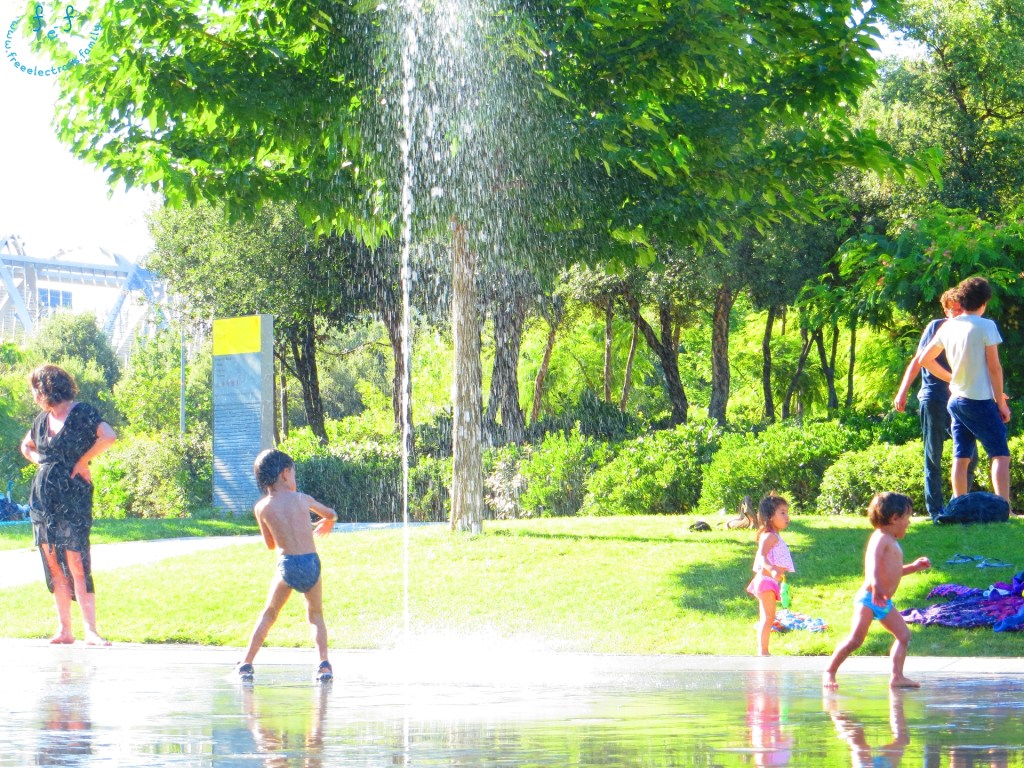 Children enjoying water play at one of the "beaches" at Madre Rio. Families, cooling off on a hot day from various watering "holes" surrounded by shady trees. #FreeElectrons.Family - camping road trip Europe, Madrid Rio water play.