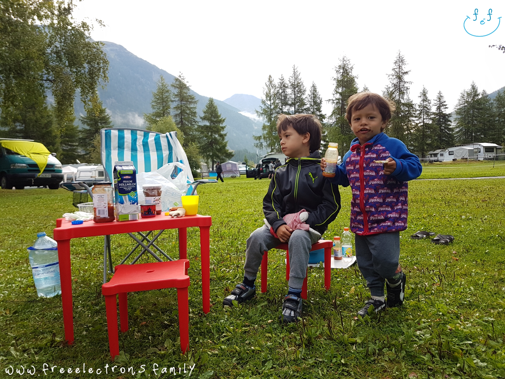 Two young kids having breakfast outdoors, at a camping site, with the Swiss alps in the background.

Nie ma jak śniadanko na świeżym powietrzu z widokiem na szwajcarskie Alpy! Nawet mi sok owocowy smakuje tutaj! Kemping Zernez, Szwajcaria.

There's nothing better than having breakfast al fresco with the view of the Swiss Alps.  Even my vegetable juice tastes good here!

www.freeelectrons.family