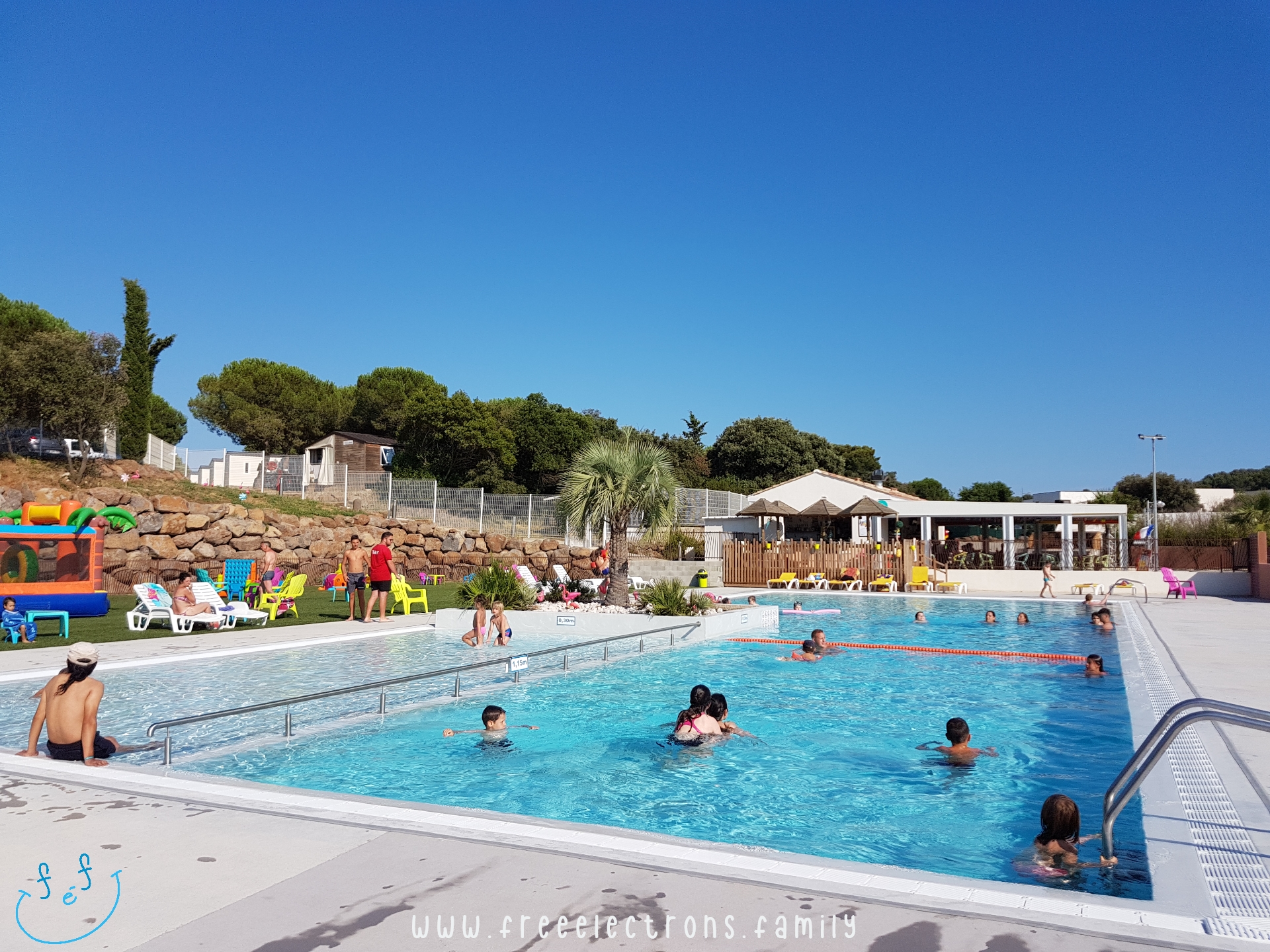 A not-so-full-of-people swimming pool divided in 3 areas, including a kiddie pool, under a summer clear blue sky.

#FreeElectrons.Family - camping road trip Europe, Agde France.