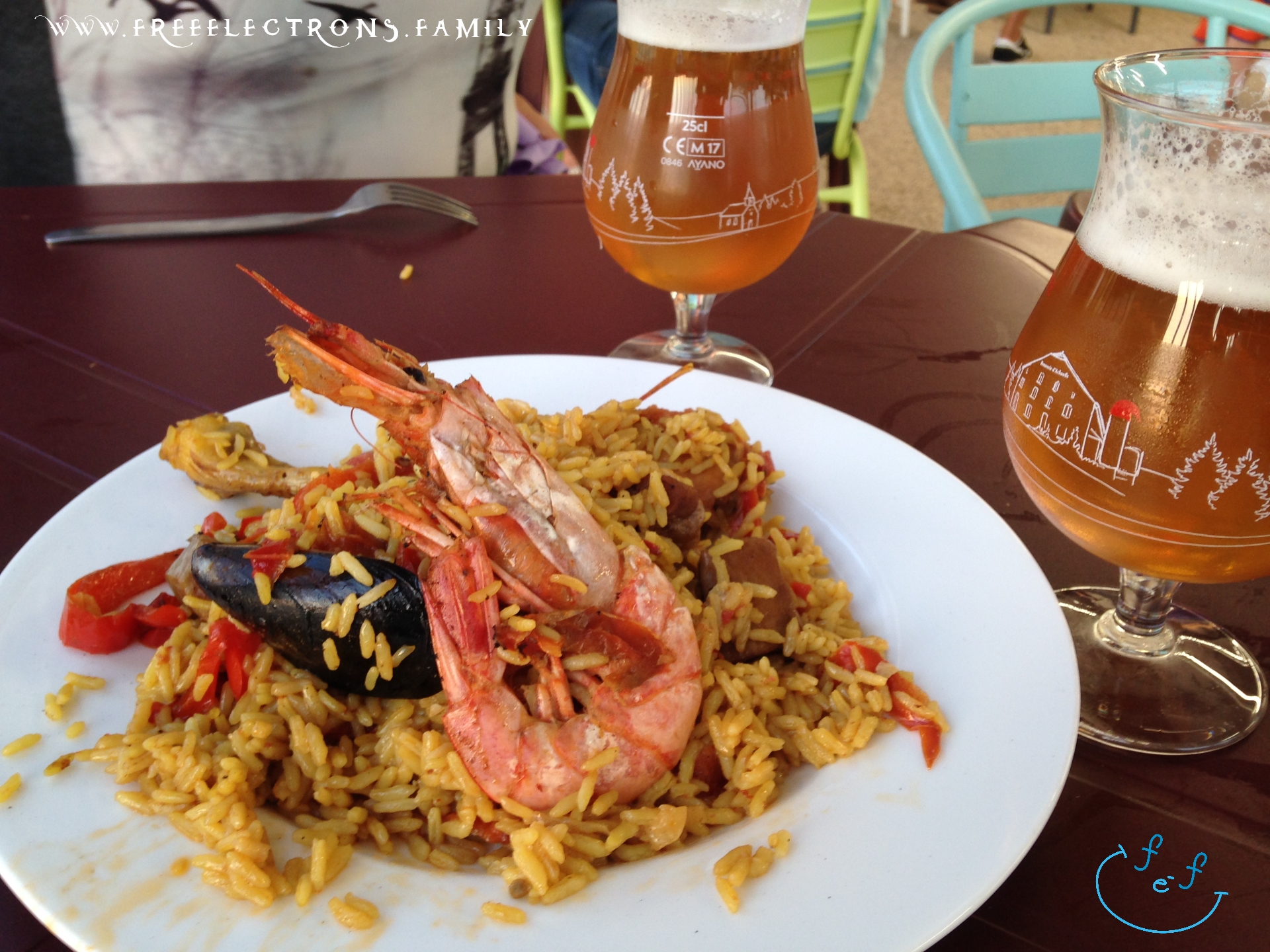 A paella (rice) dish with shrimp, mussel, chicken, strip of red bell pepper, with two sexy glasses of amber-colored local beer.

#FreeElectrons.Family - camping road trip Europe, Agde France.