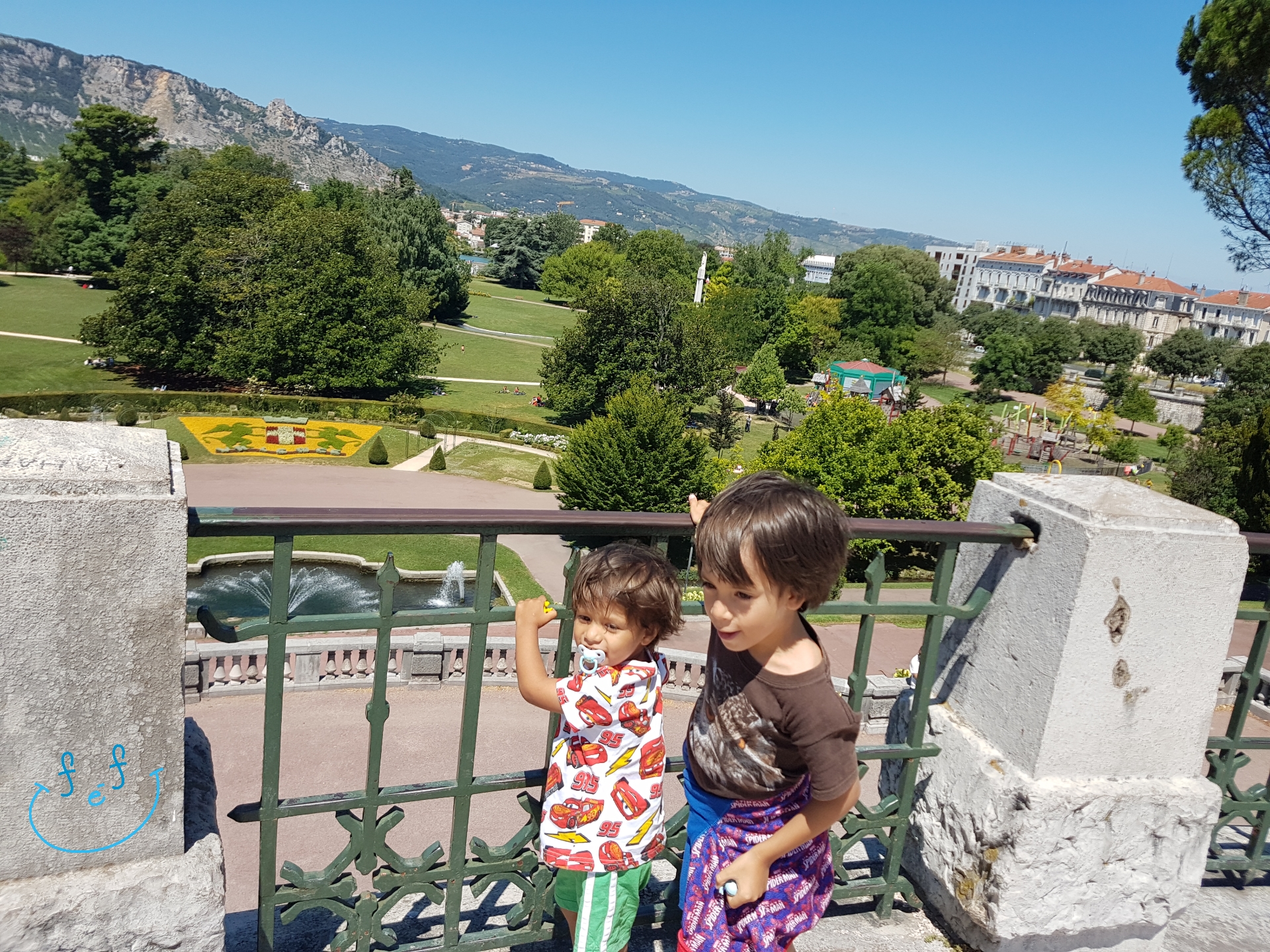 Two young children at the entrance of Parc Jouvet, overlooking the luscious greenspace of the park.

#FreeElectrons.Family - camping road trip Europe, Valence.