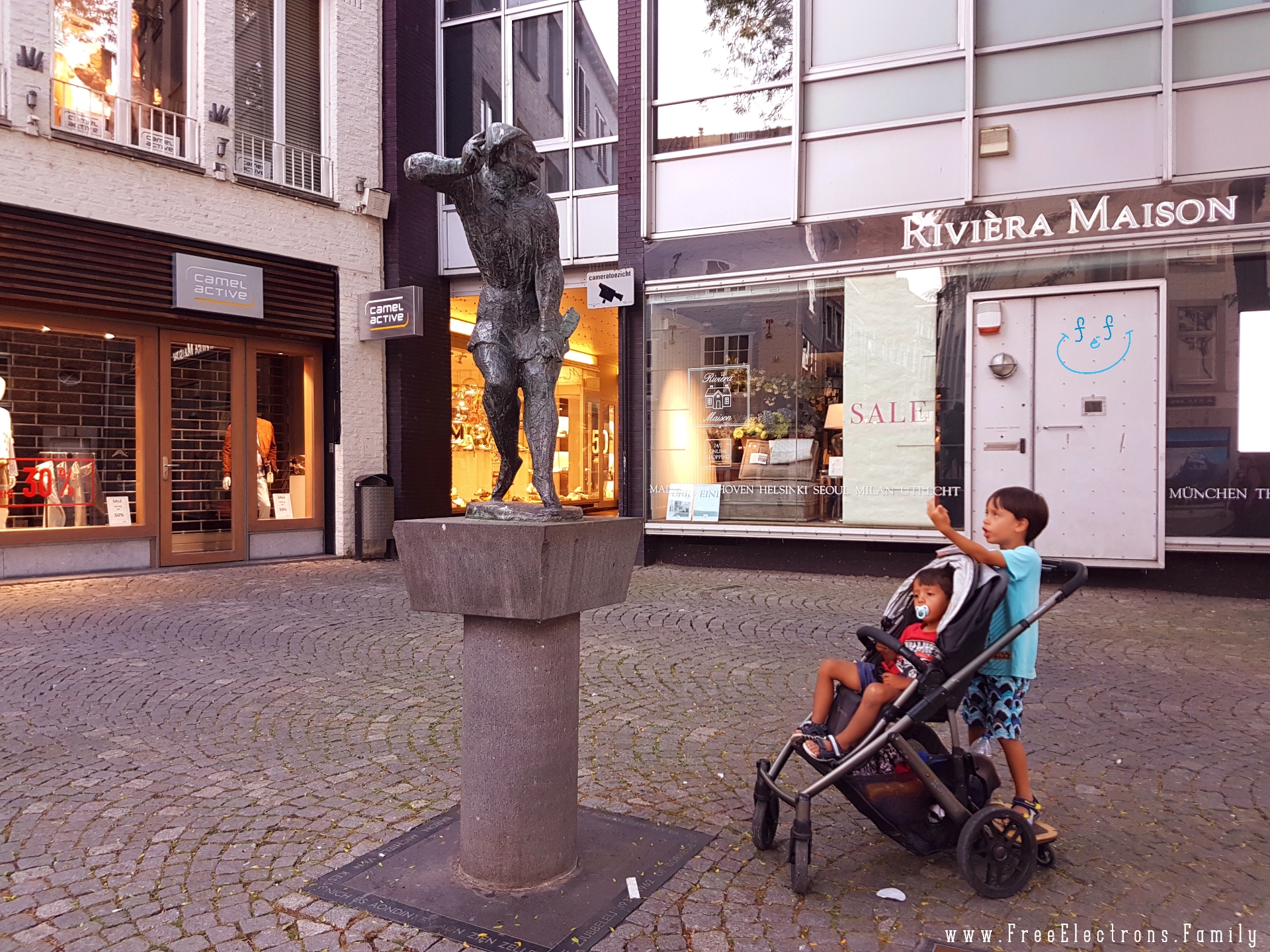  A younger child in a stroller cares less while an older one behind him mocks the statue of De Mestreechter Geis (The Spirit of Maastricht).

#FreeElectrons.Family - camping road trip Europe Maastricht