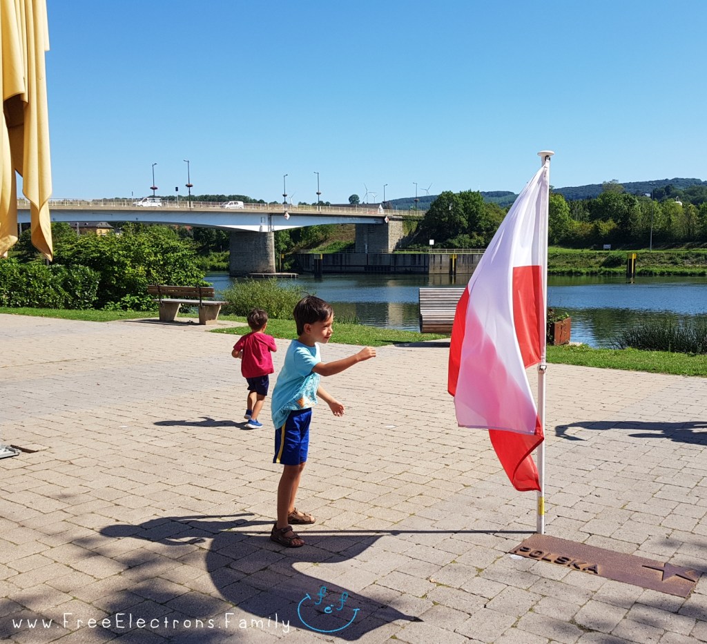 Two young boys playing in a plaza with a Polish flag; A river and a bridge in the background.

www.FreeElectrons.Family