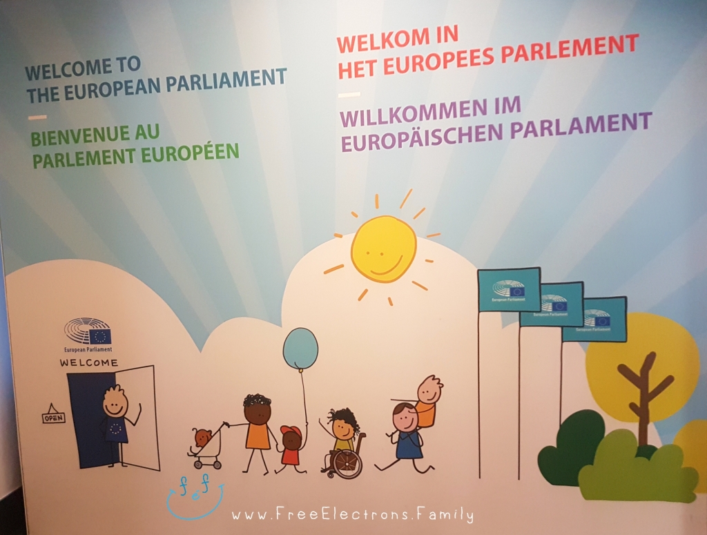"Welcome to the European Parliament" in 4 languages on a display board with caricature of families and children.

Other text on photo reads www.FreeElectrons.Family