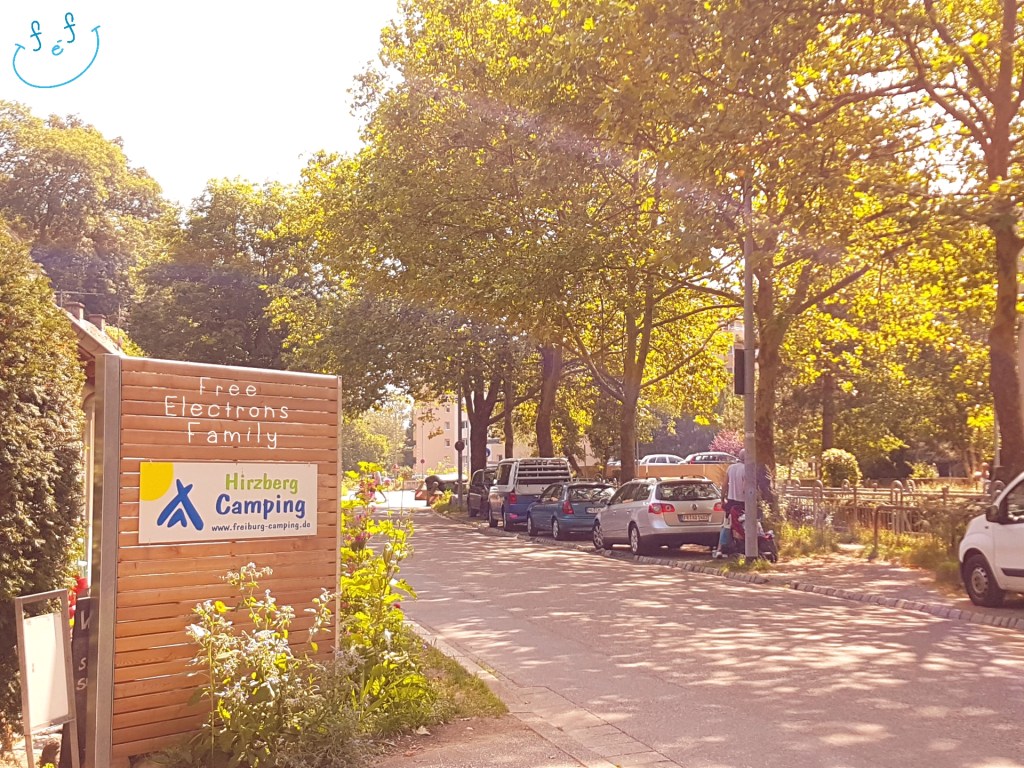 Entrance to Camping Hirzberg right off of a tree-lined main street.

Text reads: www.FreeElectrons.Family