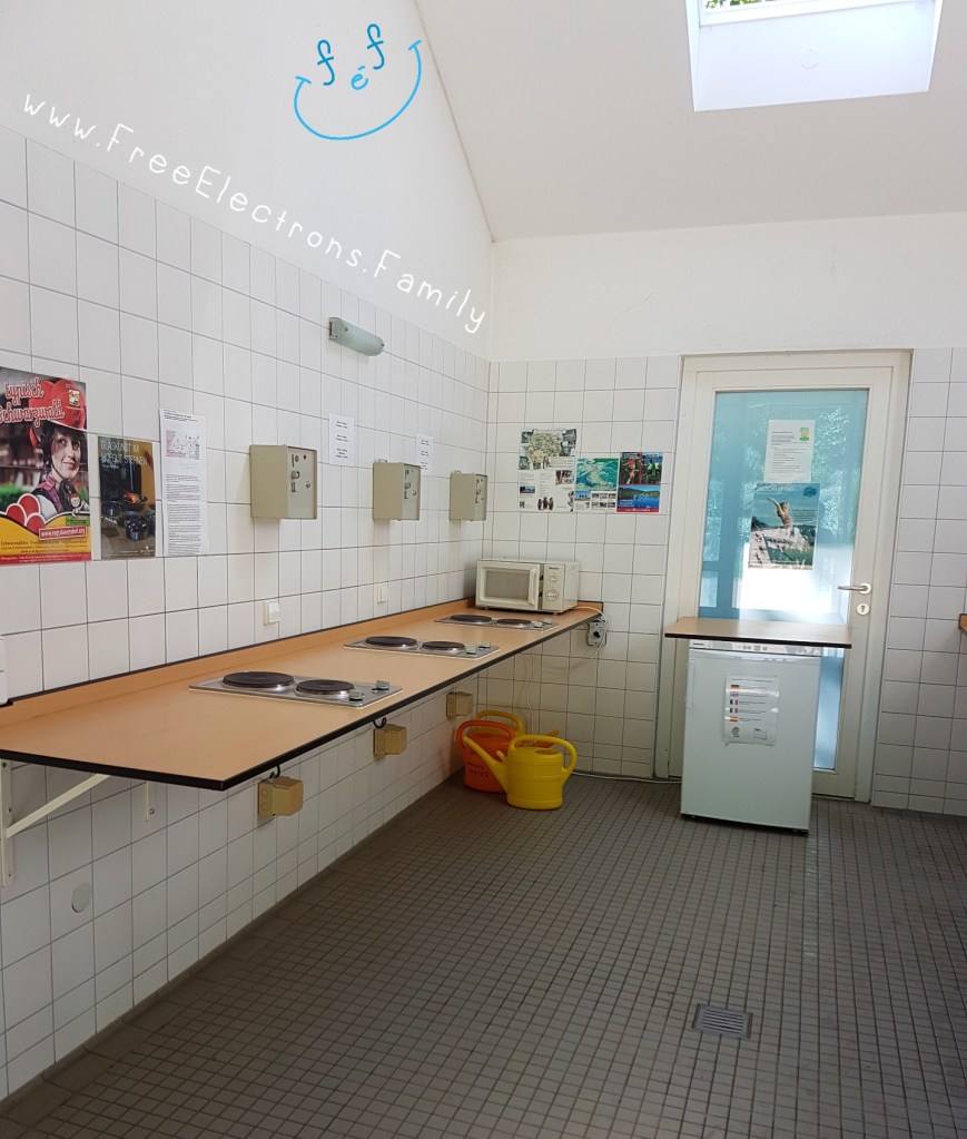 Entrance to Camping Hirzberg right off of a tree-lined main street.

Text reads: www.FreeElectrons.Family