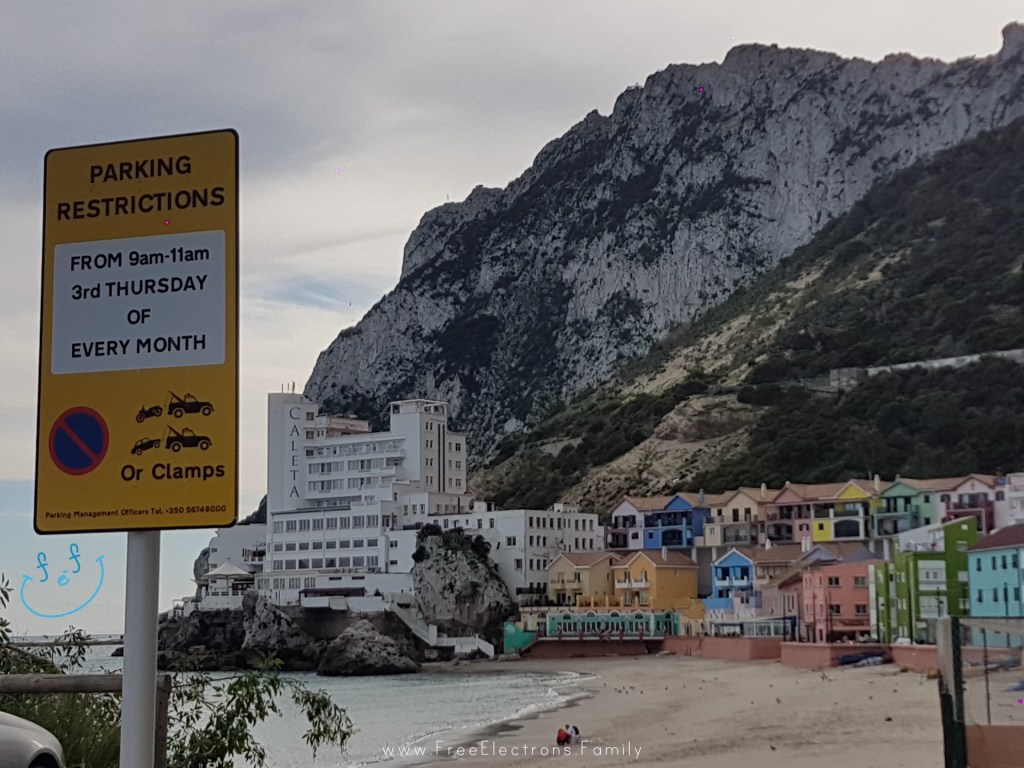 Caleta hotel colorful houses of Caleta Bay at the foot of the rock mountain of Gibraltar.  A parking signpost in the foreground.