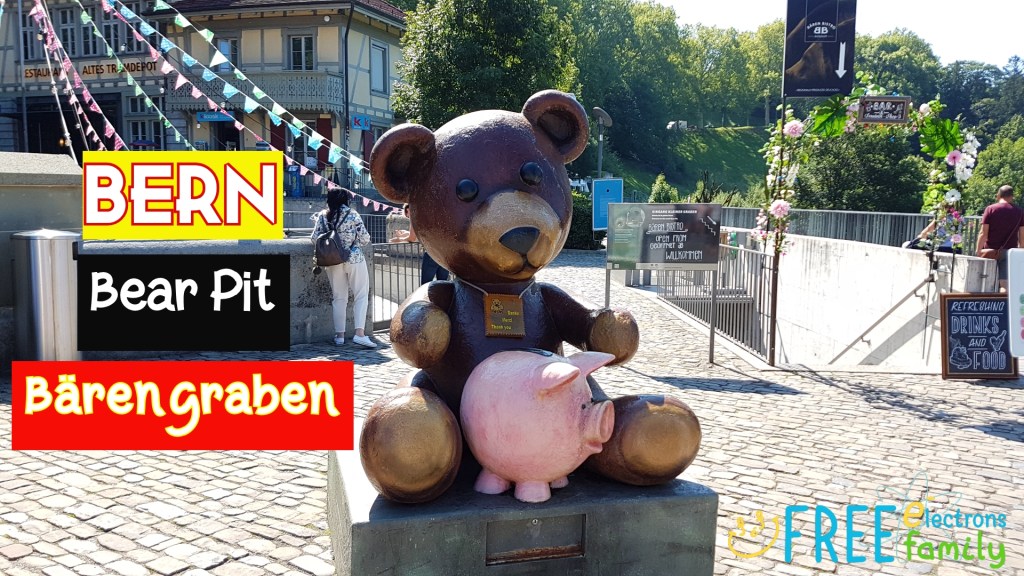 A monument of a brown bear with a pink pig.  Text reads: "BERN Bear Pit Barengraben."

www.FreeElectrons.Family 