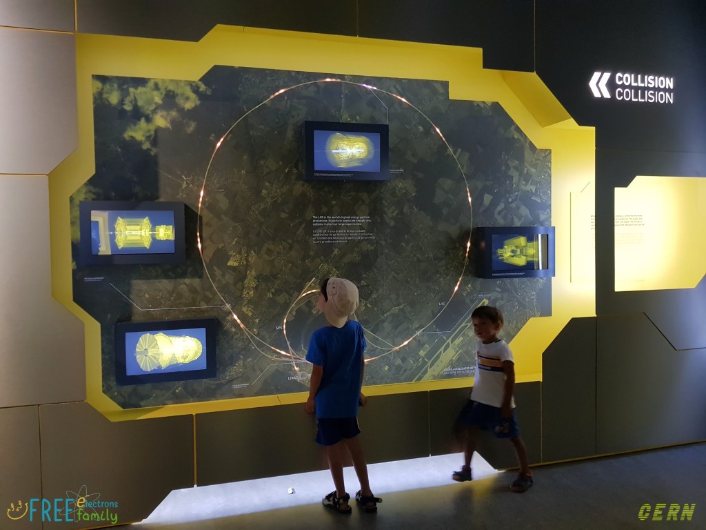 Two young children in front of a wall-sized map, showing an illustrative bird's eye view of Geneva and the outlying towns in both Switzerland and France around which the Large Hadron Collide goes.
#FreeElectrons.Family