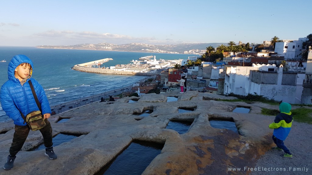 Two young boys dancing over water-filled rectangular cutouts on stone.