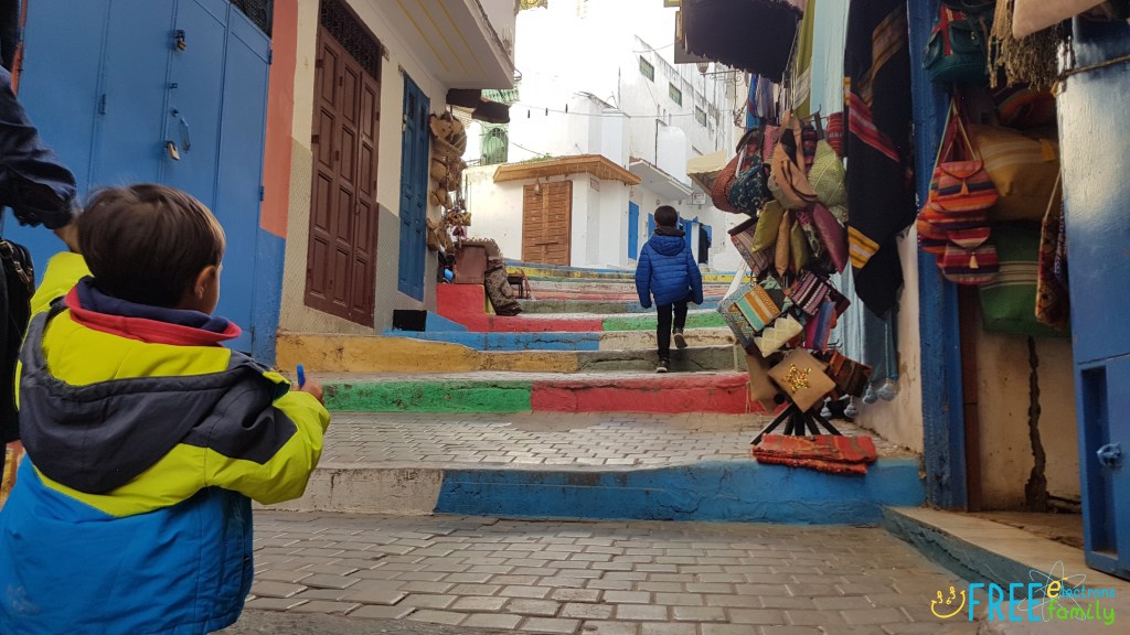 Two young boys walking uphill in a colorful and quiet street of Morocco.